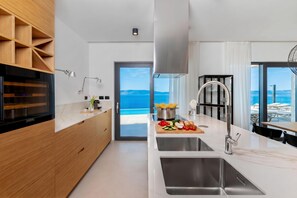 A modern kitchen with a large island, built-in appliances, and a view of the sea. - Villa rOvni, Labin, Croatia (Labin)