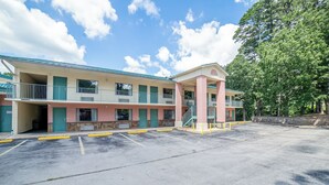 Un motel con una estructura de dos pisos, un área de estacionamiento techada y zonas ajardinadas con árboles.