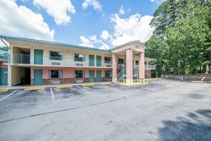 Un motel con una estructura de dos pisos, un área de estacionamiento techada y zonas ajardinadas con árboles.