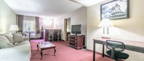 Una habitación de hotel con cama, escritorio, silla, televisión y un cuadro en la pared.