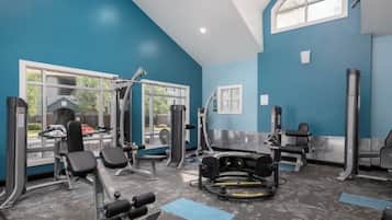 A gym with various exercise equipment, large windows, and a view of the outside.