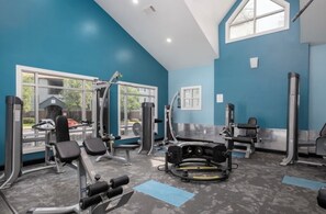 Une salle de sport équipée de divers appareils d’exercice, dotée de grandes fenêtres et offrant une vue sur l’extérieur.