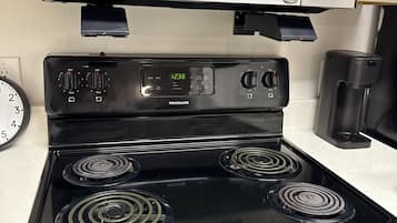 A kitchen with a black stove, a microwave, and a coffee maker.
