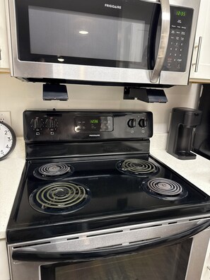 A kitchen with a black stove, a microwave, and a coffee maker. - Gainesville 3 Ensuite Bedrooms Near UF Shands Free Pool Gym Parking and WiFi (Gainesville)