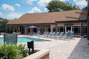 A pool area with lounge chairs and a brick building in the background. - Gainesville 3 Ensuite Bedrooms Near UF Shands Free Pool Gym Parking and WiFi (Gainesville)