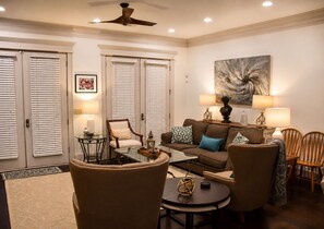 A well-lit living room with a sofa, chairs, a coffee table, and a ceiling fan.
