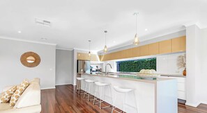 A modern kitchen with a central island, bar stools, and pendant lighting. - Terrace Eleven - Echuca Holiday Homes (Echuca)