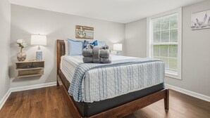 Un dormitorio con cama, lámparas de noche, mesita de noche y ventana con persianas.