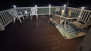 Una terraza con mesa y sillas de vidrio, rodeada por una barandilla blanca.