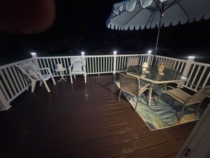 A deck with a glass table and chairs, surrounded by a white railing. - Quiet Coastal Retreat near Atlantic Beach  3-bedroom house in Beaufort NC (Beaufort)
