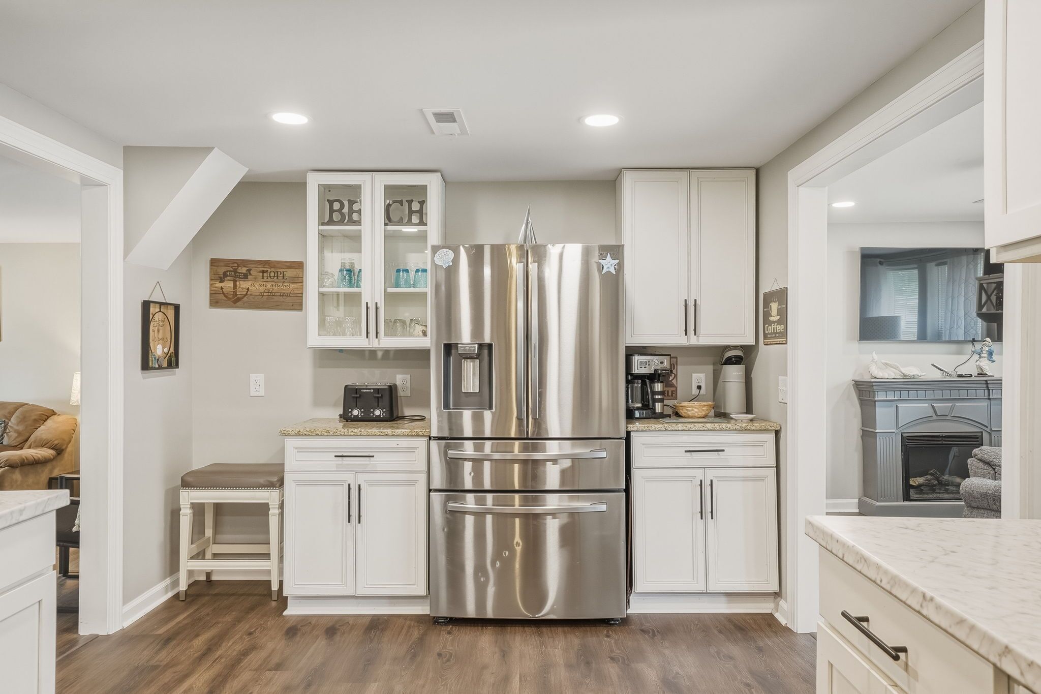 A modern kitchen with white cabinetry, a stainless steel refrigerator, and a built-in water dispenser.