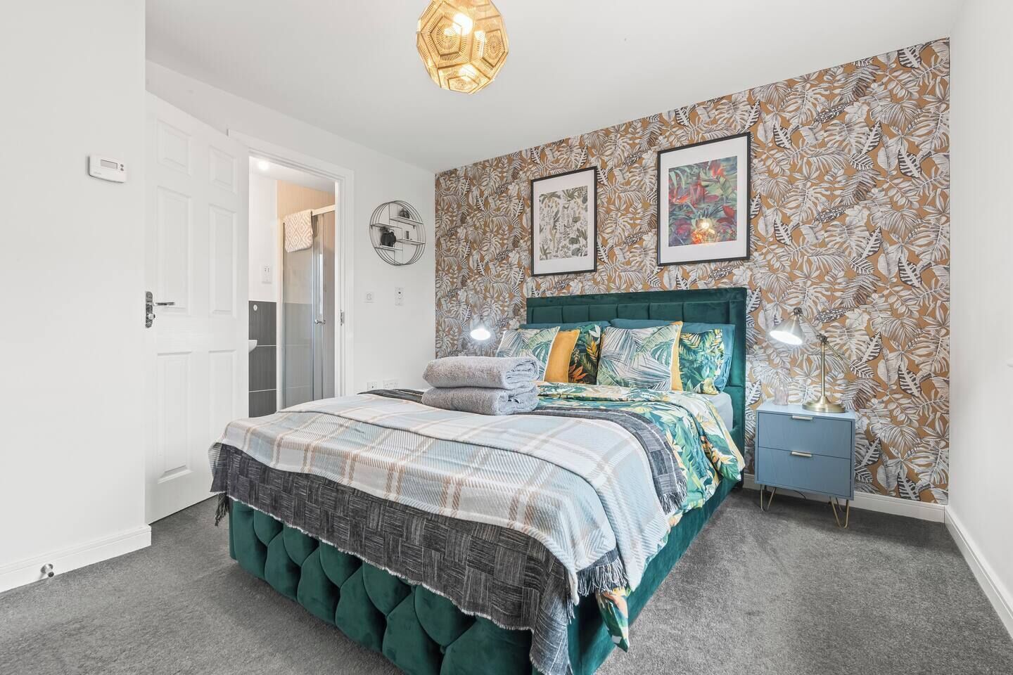 A bedroom with a bed, a nightstand, a wall clock, and a door.