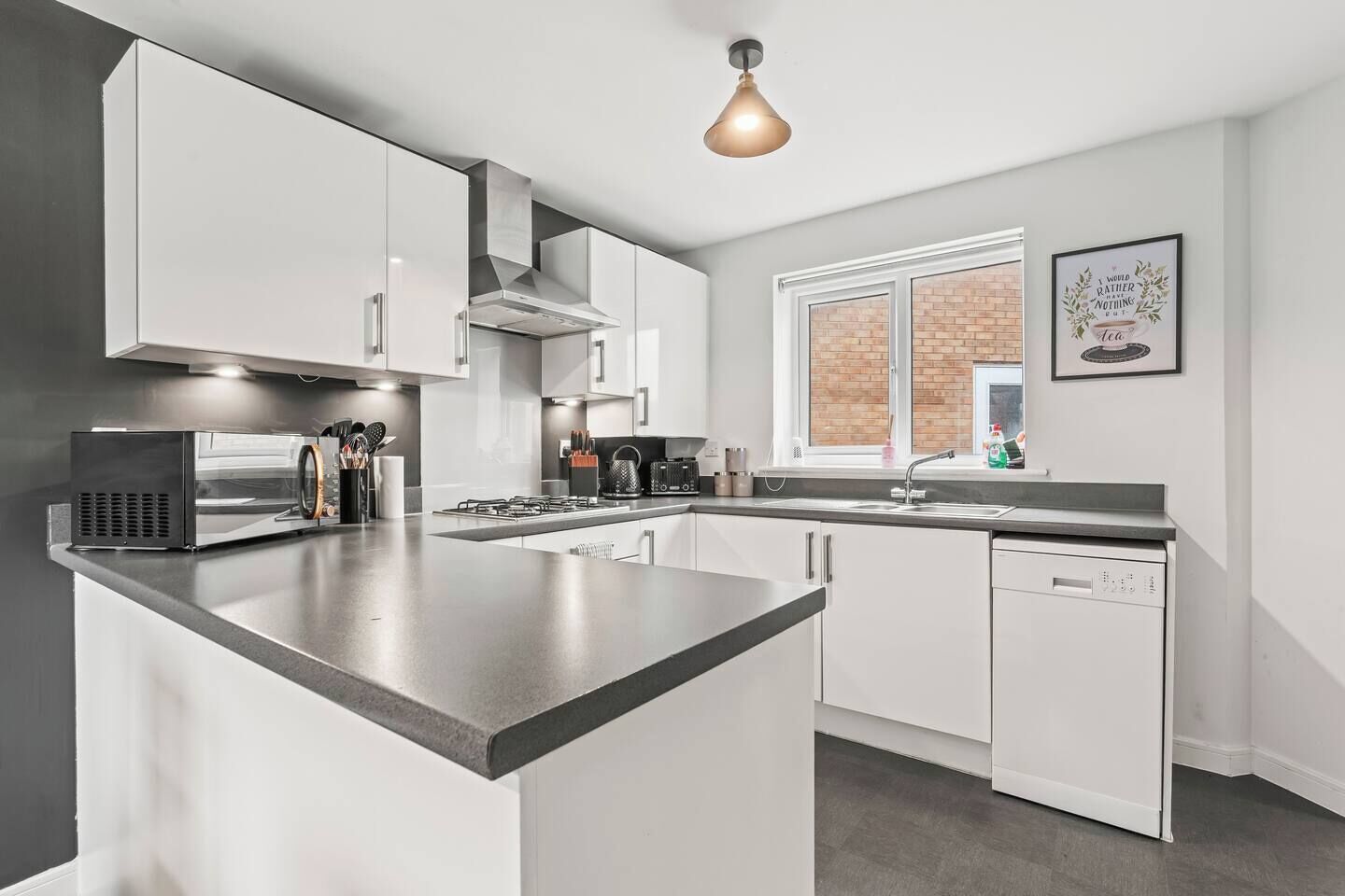 A modern kitchen with a central island, stainless steel appliances, and a hanging light fixture.