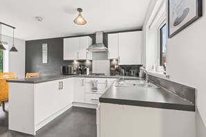 Una cocina moderna con gabinetes blancos, electrodomésticos de acero inoxidable y una encimera negra.
