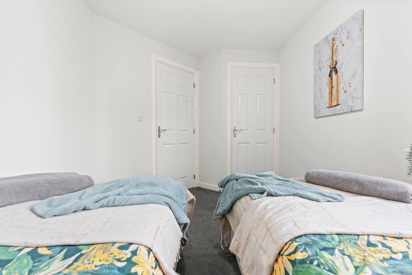 A room with two beds, white walls, and a door.