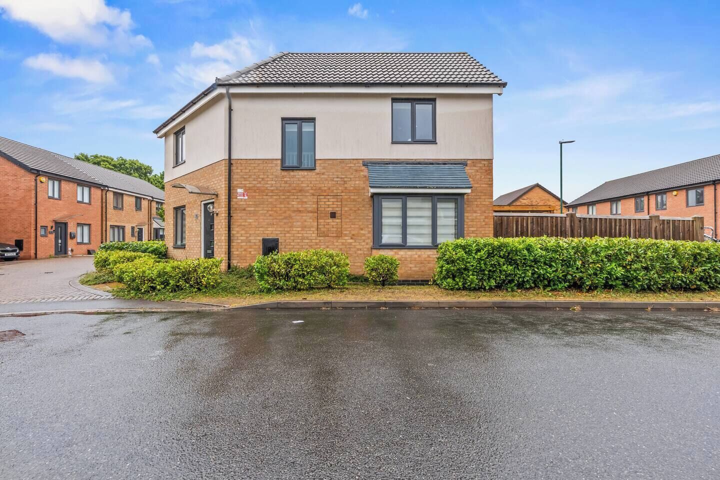 A two-story residential building with a brick facade, a flat roof, and a gated driveway.