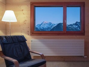 A room with a wooden chair, a window with a mountain view, and a radiator. - Labbrunnu OG 5-Bettwohnung, Dusche, WC 5-Bettwohnung, Dusche, WC by Interhome (Rosswald)