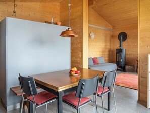 A modern interior with a wooden dining table, two chairs, a sofa, and a fireplace. - Labbrunnu OG 5-Bettwohnung, Dusche, WC 5-Bettwohnung, Dusche, WC by Interhome (Rosswald)