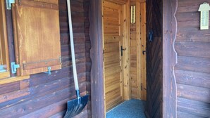 A wooden cabin interior with a door, a shovel, and a small cabinet. - Chalet Glimuschir Appartement/Fewo, Dusche, WC Appartement/Fewo, Dusche, WC by Interhome (Rosswald)