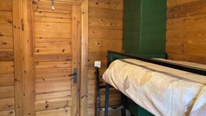 A wooden room with a single bed, a green cabinet, and a door. - Chalet Glimuschir Appartement/Fewo, Dusche, WC Appartement/Fewo, Dusche, WC by Interhome (Rosswald)