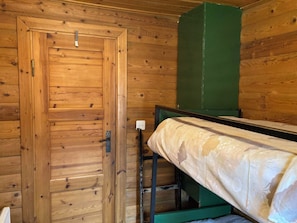 A wooden room with a single bed, a green cabinet, and a door. - Chalet Glimuschir Appartement/Fewo, Dusche, WC Appartement/Fewo, Dusche, WC by Interhome (Rosswald)