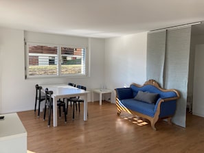 Una habitación con una mesa de comedor, sillas, un sofá y una ventana con persianas.