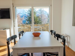 Een eetruimte met een witte tafel, zwarte stoelen en een rieten kom.