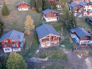 A cluster of wooden cabins with sloped roofs, surrounded by trees and a grassy area.