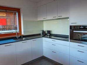 A modern kitchen with white cabinets, a stainless steel sink, and a coffee maker.