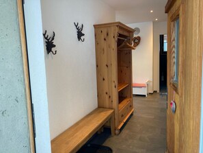 A hallway with a wooden bench, a wardrobe, and a bed in the background.