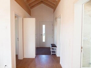 A narrow hallway with wooden flooring, white walls, and a door at the end.