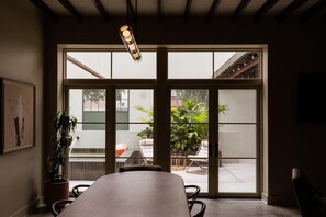 A room with a large sliding glass door leading to an outdoor area with a table, chairs, and a potted plant. - The Diamond | Private Courtyard Retreat (New Orleans)