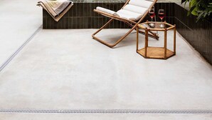 Un área de piscina exterior moderna con sillones de descanso, una piscina pequeña y plantas en macetas.