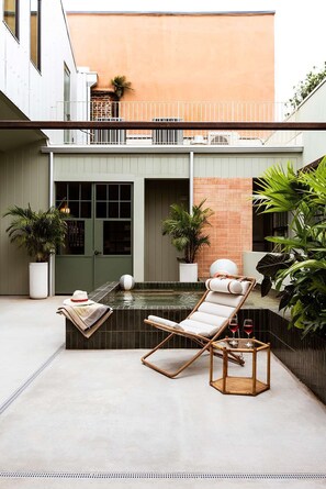 Un espace piscine extérieur moderne, doté de chaises longues, d’un petit bassin et de plantes en pot.