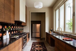 Une cuisine moderne dotée d’un îlot central, d’appareils électroménagers en acier inoxydable et offrant une vue sur le salon attenant.