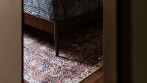 Un dormitorio con una cama, un tapete estampado y una lámpara fijada a la pared.