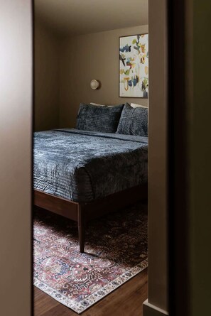 Une chambre à coucher avec un lit, un tapis à motifs et un luminaire fixé au mur.