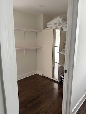 A walk-in closet with open shelving and a mirrored closet door.