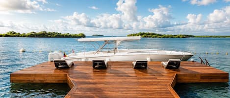 A wooden dock extending into a calm body of water with a boat moored at the end.
