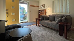 A living room with a sofa, a coffee table, a door, and a window with shutters. - Hyde Park "Rail Trail" Entire House (Cincinnati)