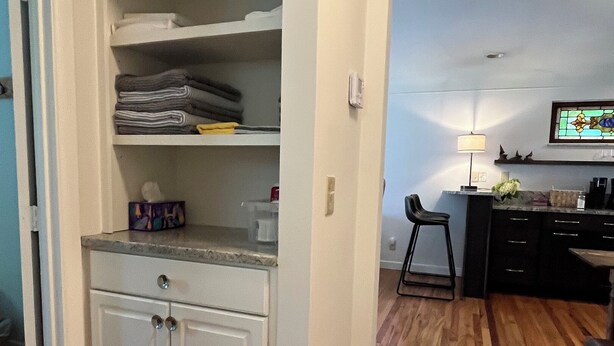 A compact kitchen with a built-in pantry, a dining area with a chair, and a small bar area. - Hyde Park "Rail Trail" Entire House (Cincinnati)