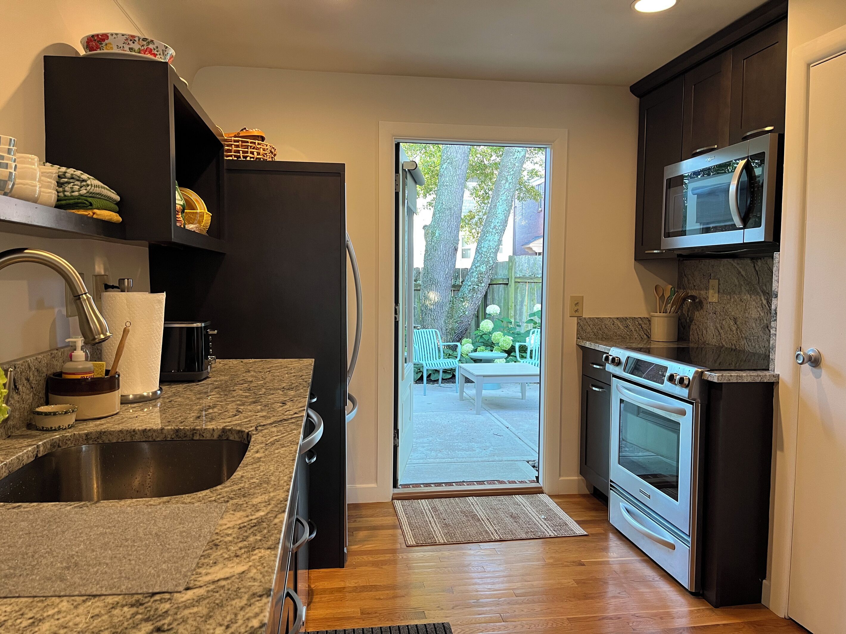 A modern kitchen with granite countertops, a stainless steel sink, a built-in oven, and a microwave.