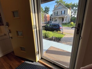 Eine Tür, die zu einer Veranda mit Blick auf eine Straße und ein Haus führt.