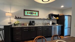 A modern kitchen with a central island, dark cabinetry, a built-in oven, and a refrigerator. - Hyde Park "Rail Trail" Entire House (Cincinnati)