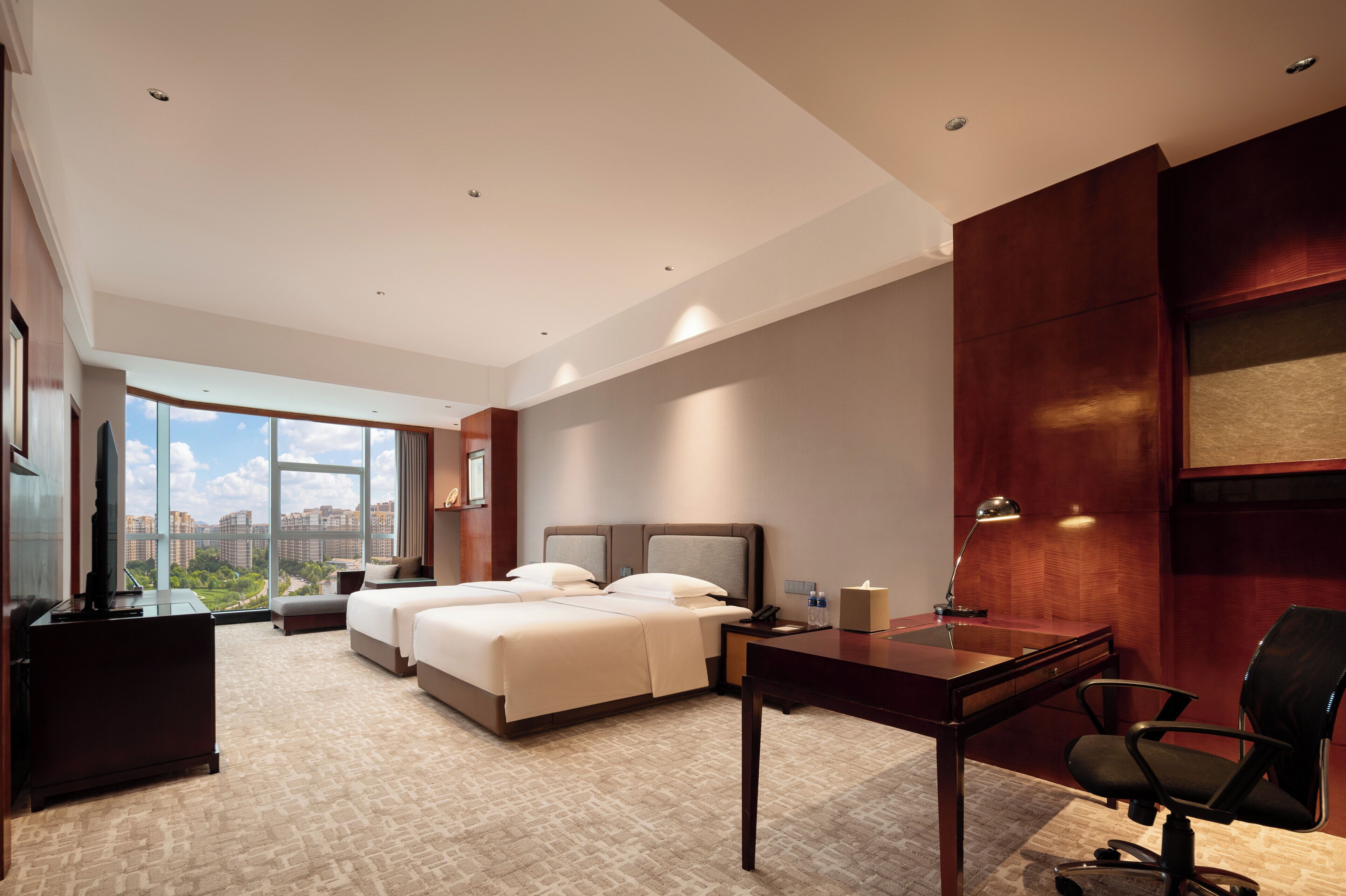 Una habitación de hotel con una cama grande, un escritorio, una silla y un televisor.