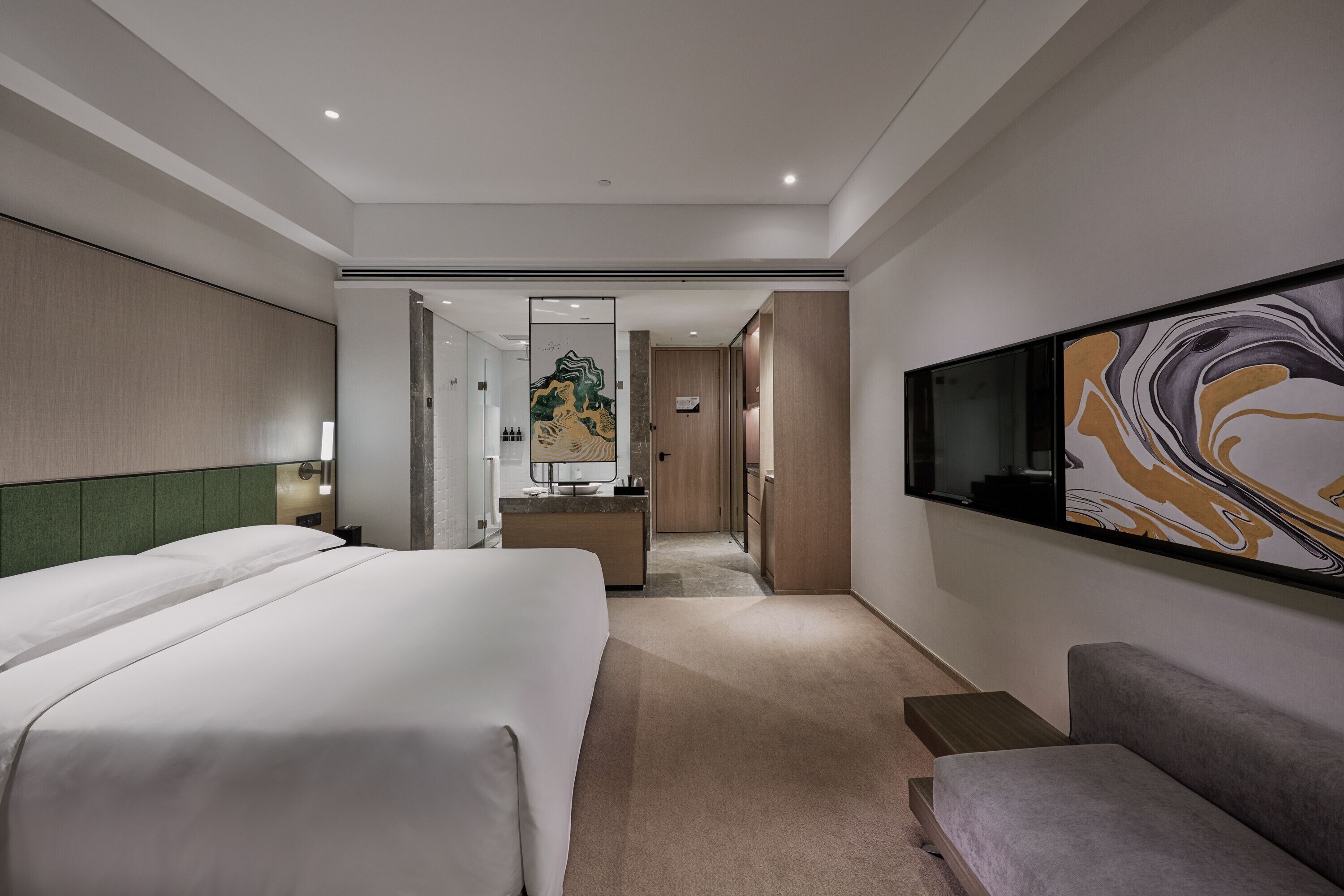 A hotel room with a large bed, a desk, a TV, and a painting on the wall.