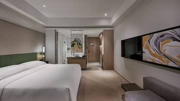 A hotel room with a large bed, a desk, a TV, and a painting on the wall.