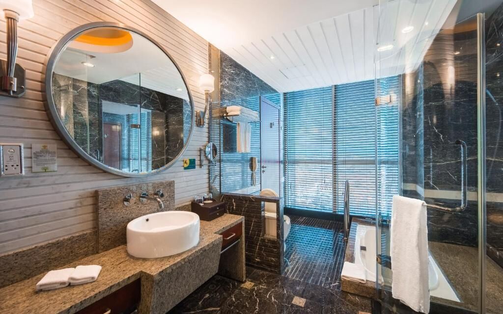 A modern bathroom with a round mirror, a sink, and a glass shower enclosure.