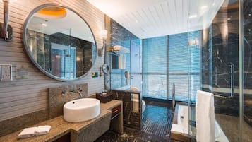 A modern bathroom with a round mirror, a sink, and a glass shower enclosure.