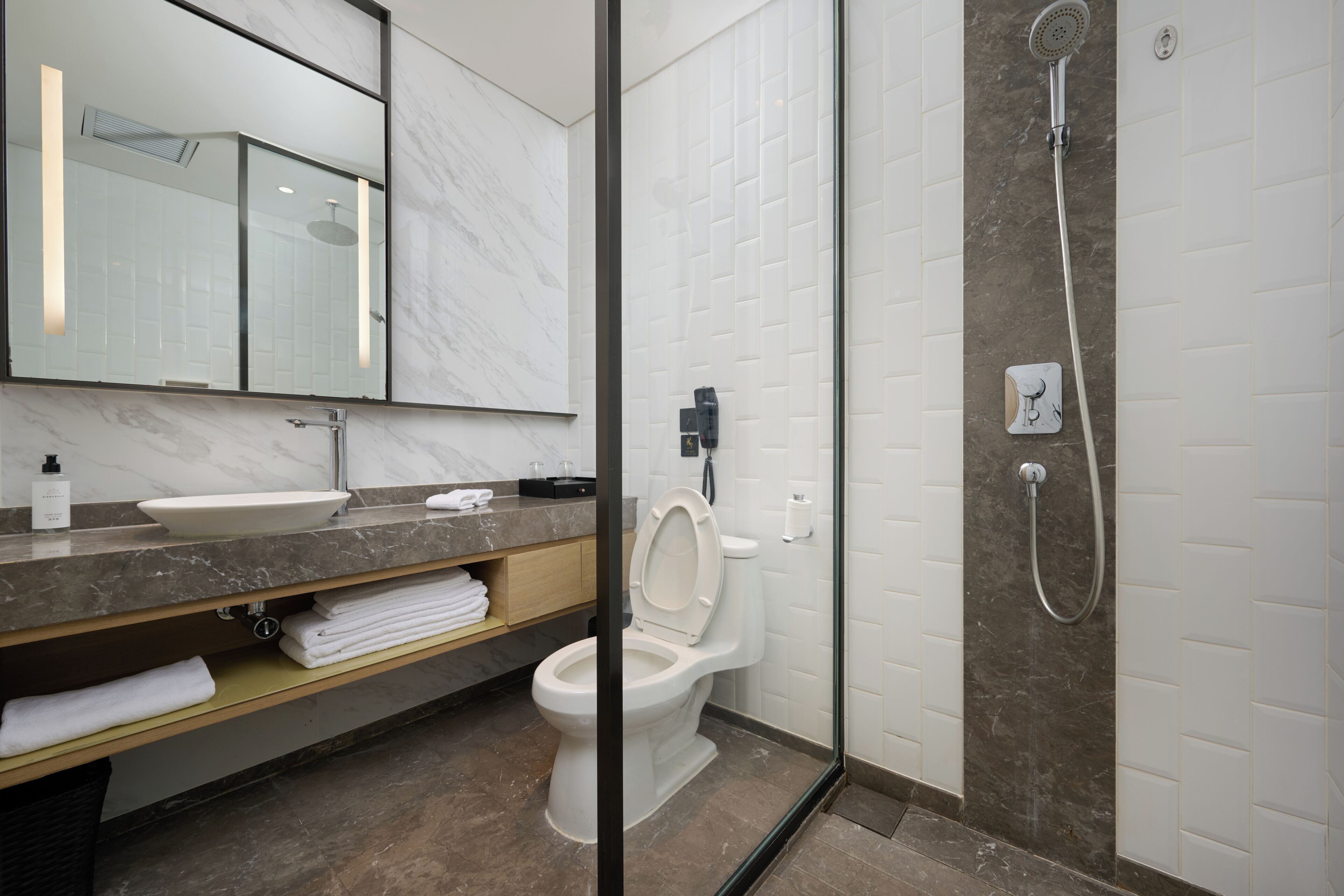 Un baño moderno con tocador de mármol, inodoro y zona de ducha.